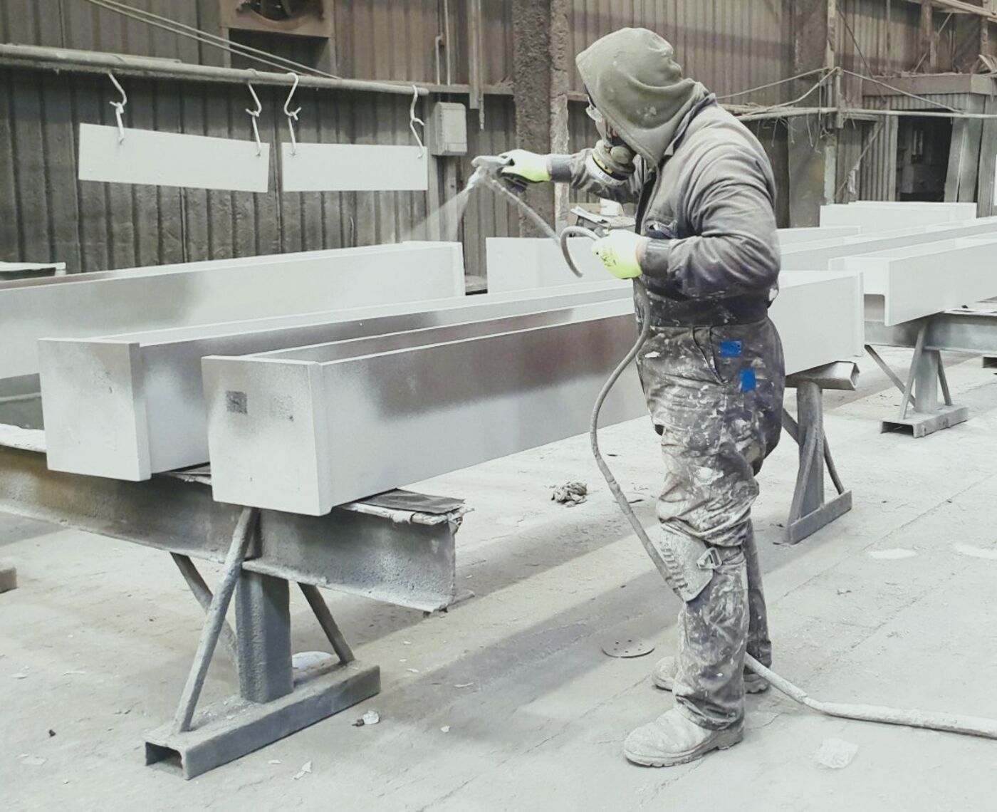 A painter spraying steel beams in a workshop